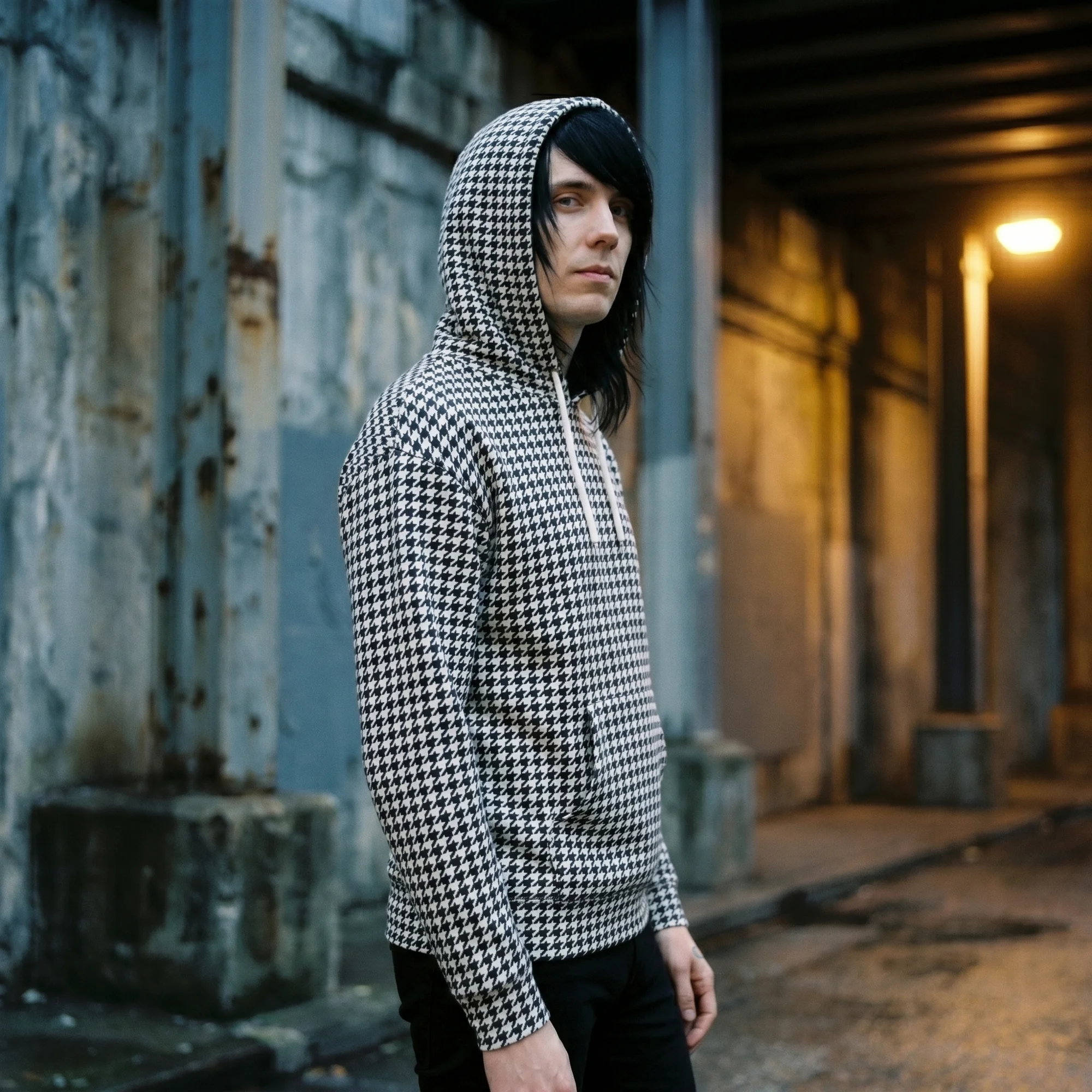 Man wearing a black and white houndstooth hoodie with the hood up, side view