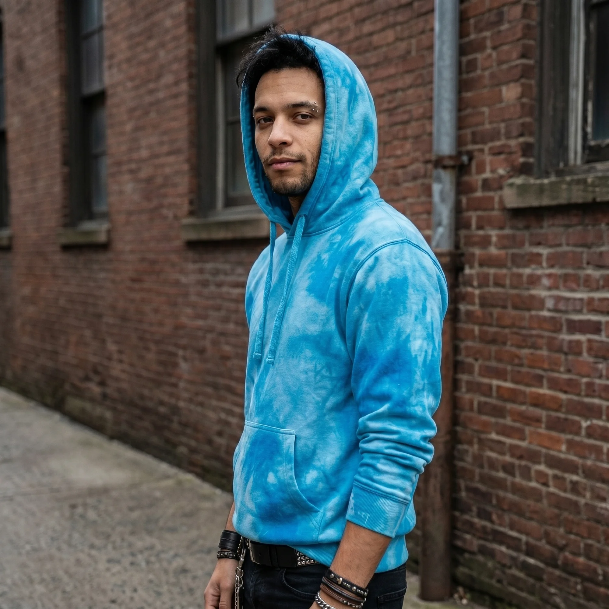 Man wearing an aqua tie-dye hoodie with the hood up, side view
