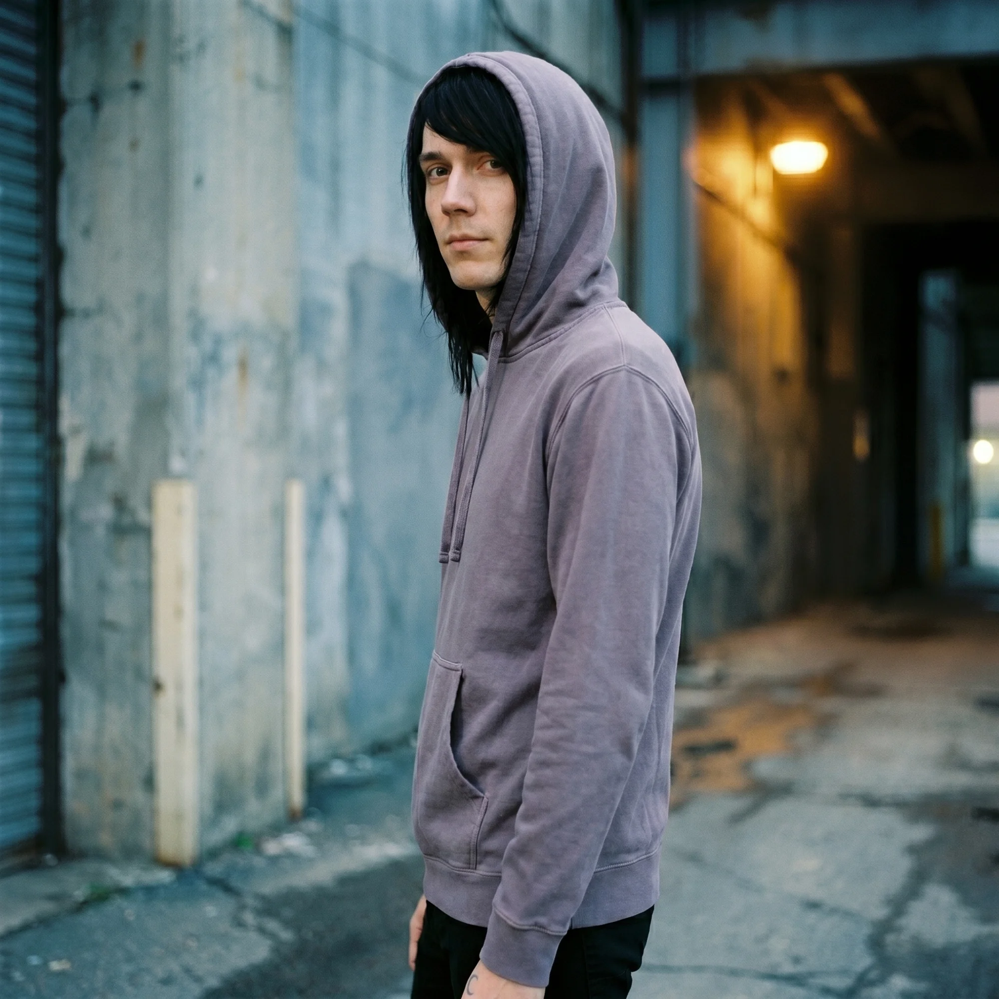 Man wearing a plum pigment dye hoodie with the hood up, side view
