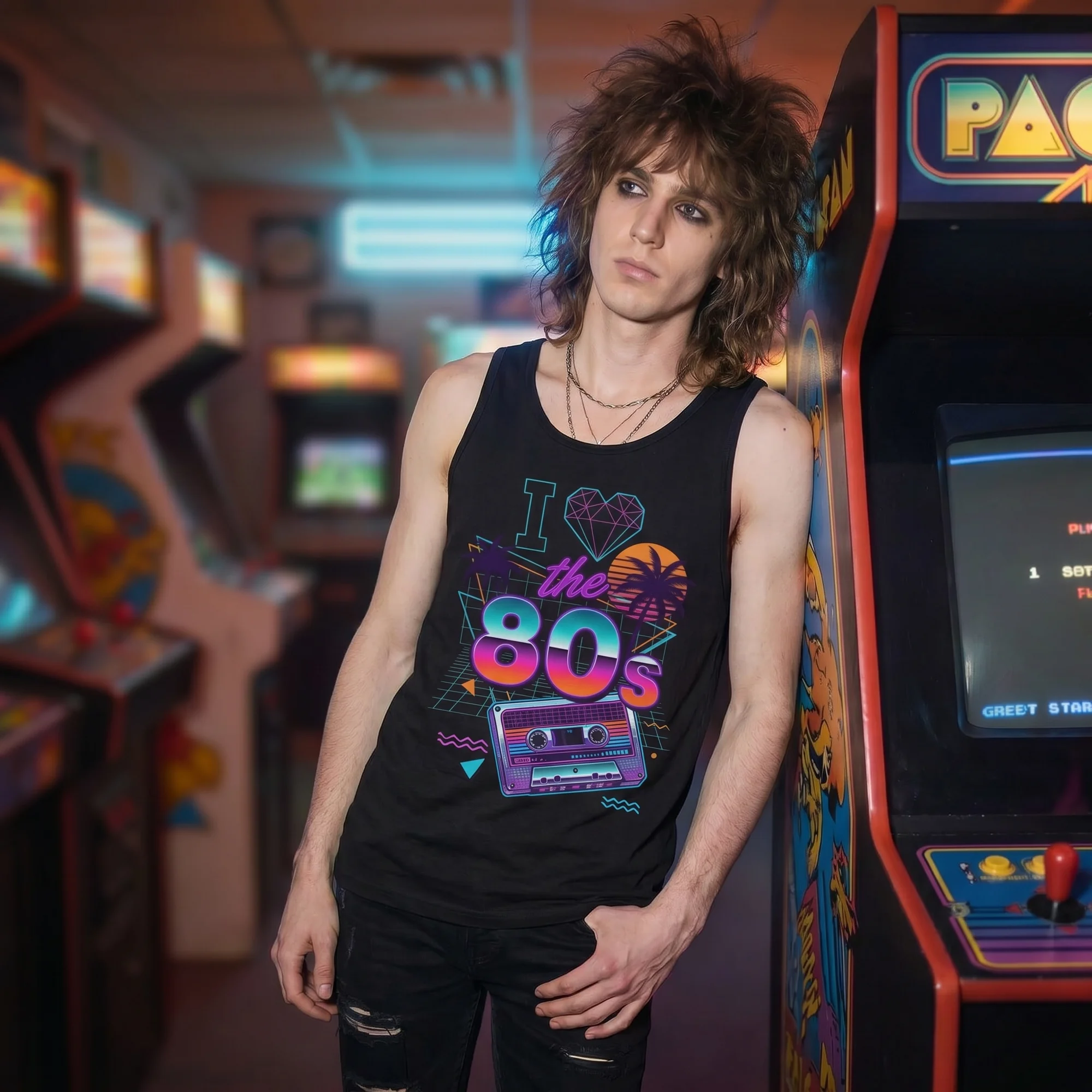 Man with shaggy hair leaning against a Pac-Man arcade cabinet wearing a black I Love the 80s tank top, side view